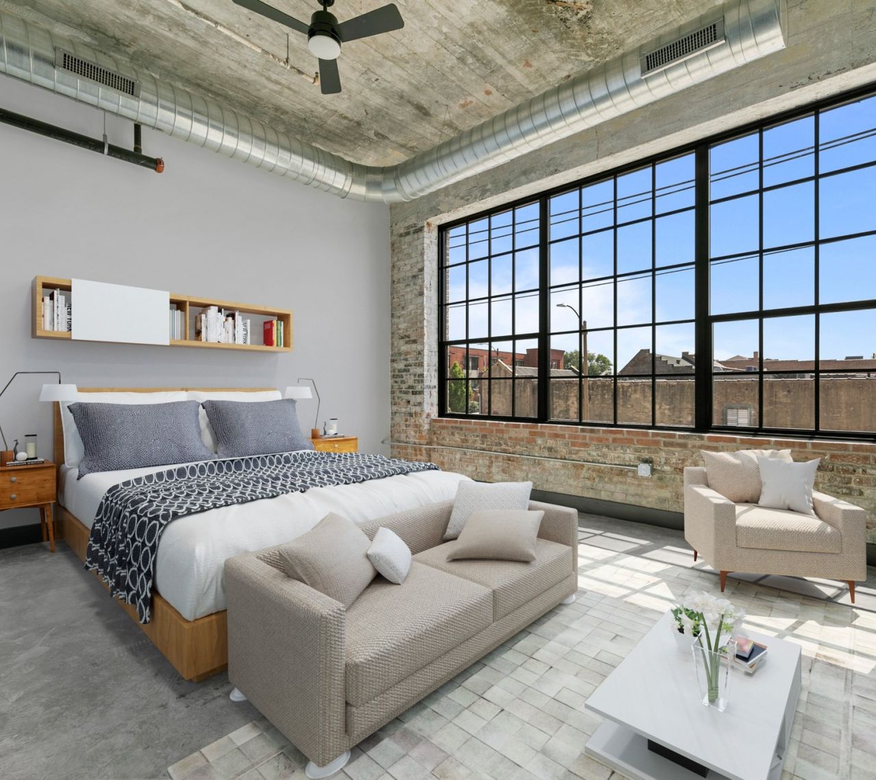 The Nash studio apartment bedroom with large windows, exposed brick, and 12 ft ceilings