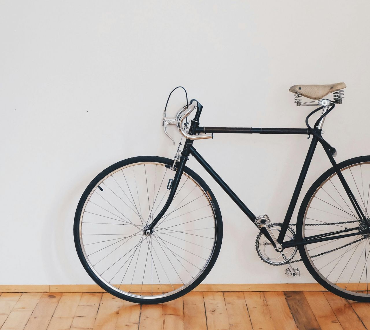 Black road bike resting against a white wall